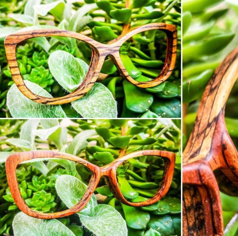 Fusione con la natura: occhiali da sole in legno con lenti specchiate verdi, esposti tra le foglie per evocare l'origine naturale del materiale.