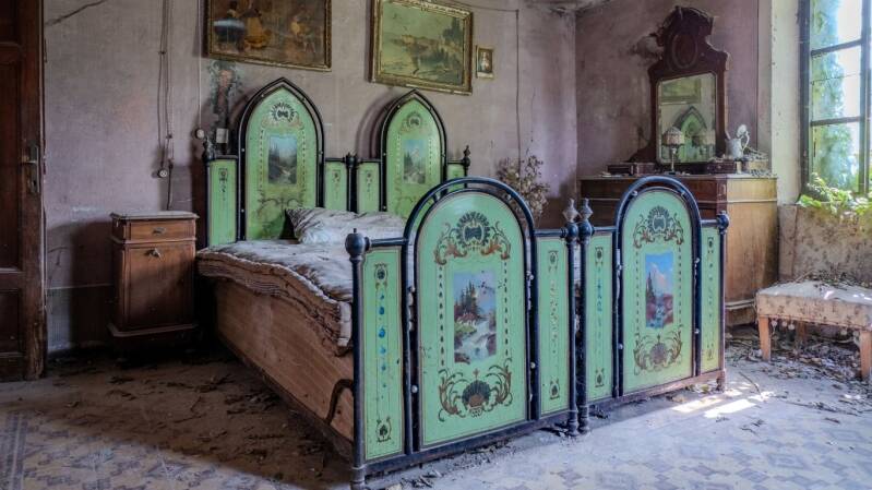 Verlaten slaapkamer in Villa Letto Verde in Italië met opvallend groen vintage bed, oude houten meubels, vervallen muren en natuurlijke lichtinval tijdens urban exploration fotografie door Wandering in Dreams