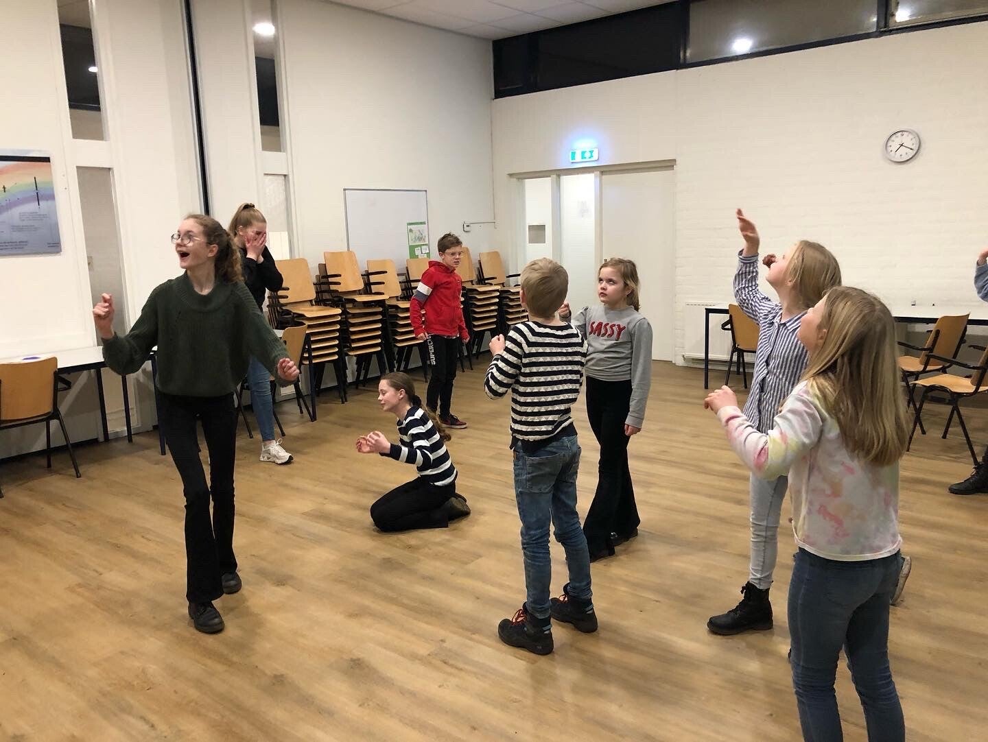 Theaterworkshops. Op de foto staat een groep kinderen die allemaal voor zich spelen dat ze op een bepaalde plek zijn.