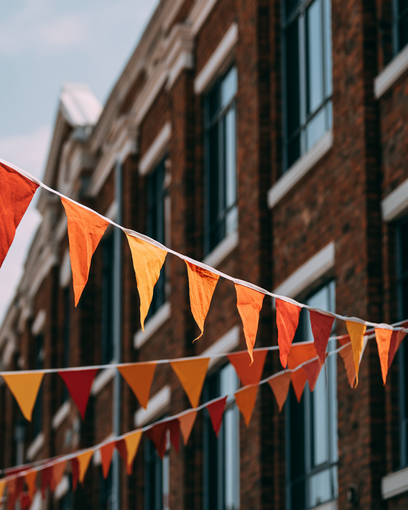 Minimal orange bunting flags against a clear blue sky, showing orange as a festive Dutch colour connected to King’s Day, football supporters and national celebration.