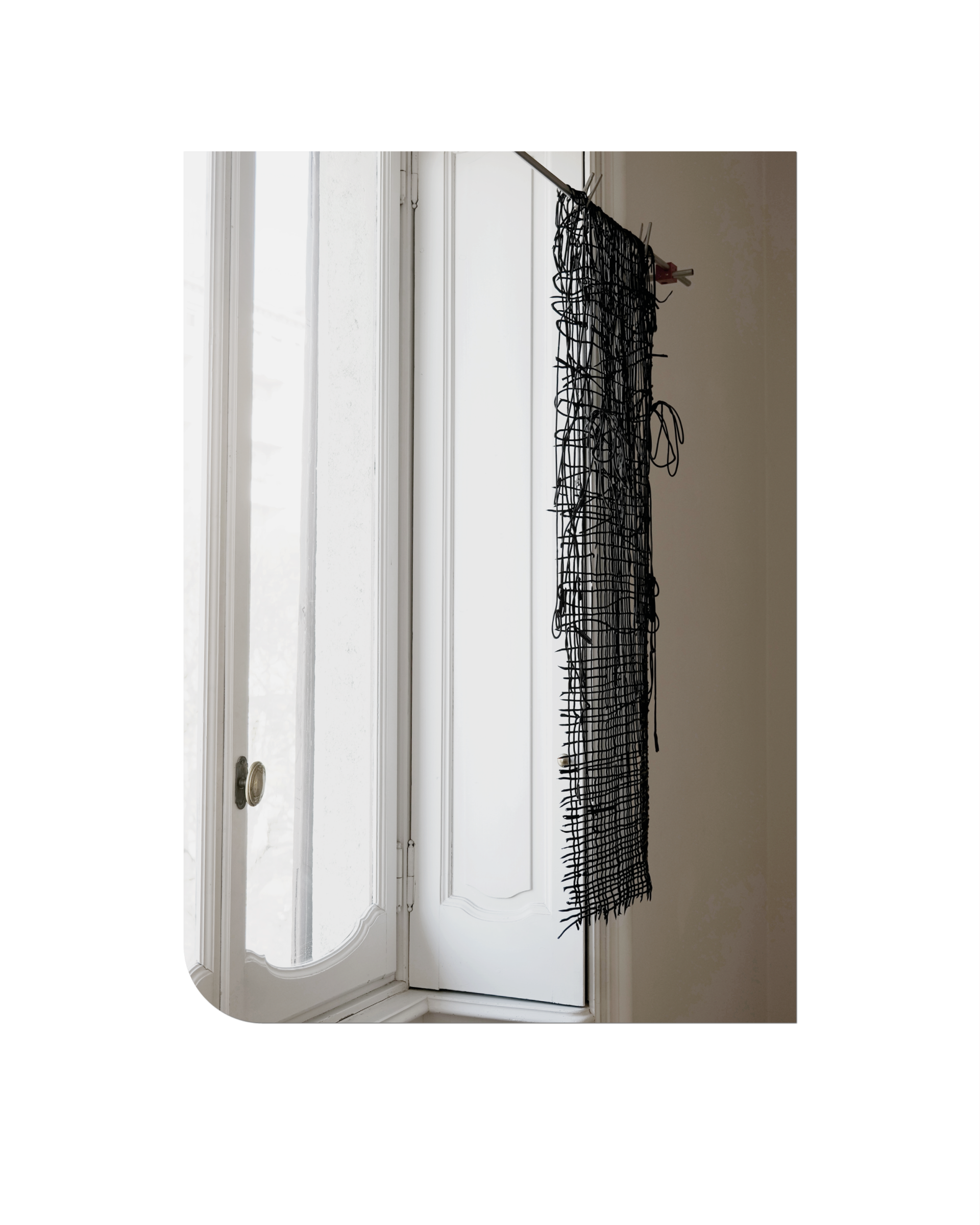 Textile installation from Romantic Brutalism at Milan Design Week 2025, with black threads creating a delicate contour in space.