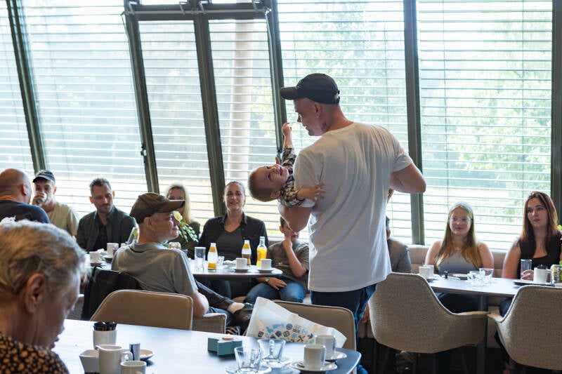 vader speelt met zoon tijdens baby uitvvaart
