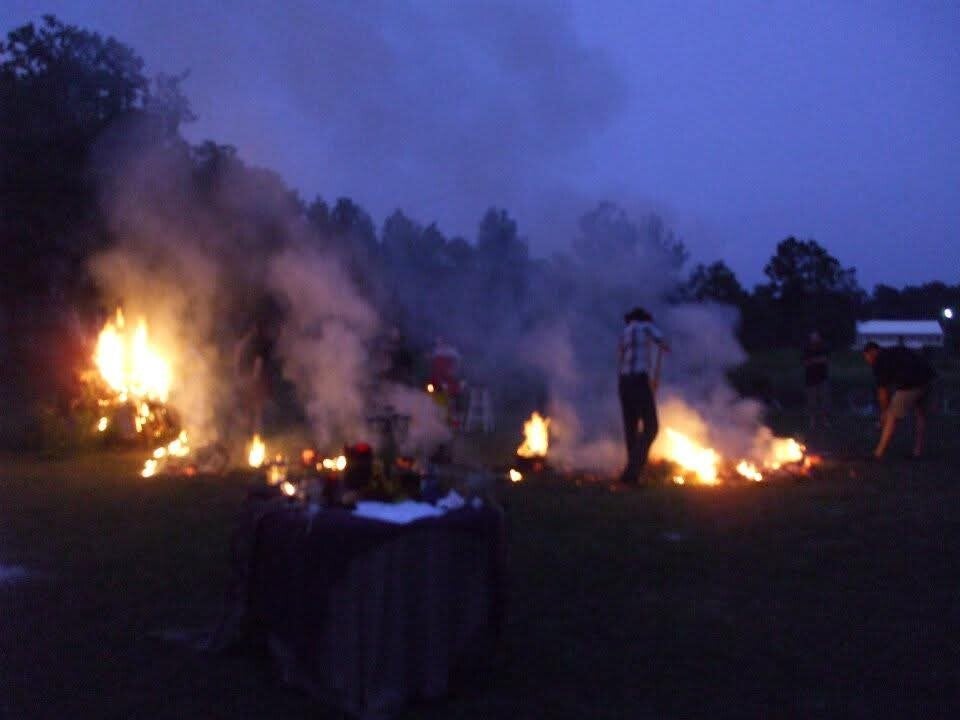 Participants raking up the remains of the Wickerman to start the bonfire.
