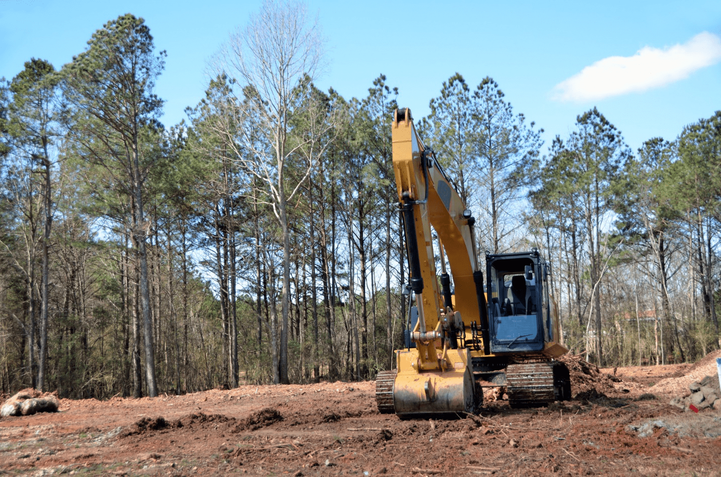 Excavator removing trees and stumps from land for future construction 