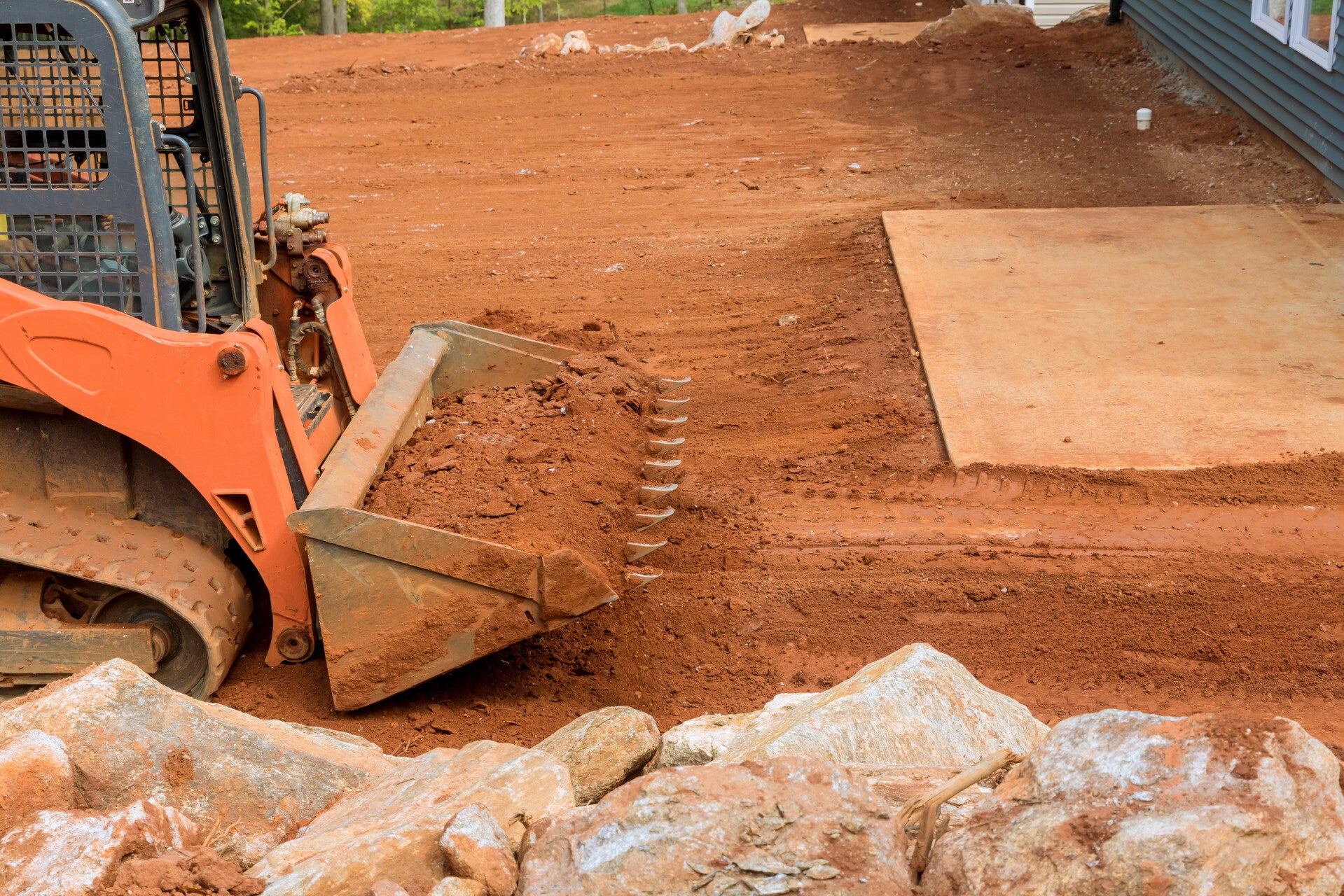 Skid steer spreading dirt on construction site to prep for future building  
