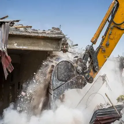Excavator bucklet demolishing the roof of a building