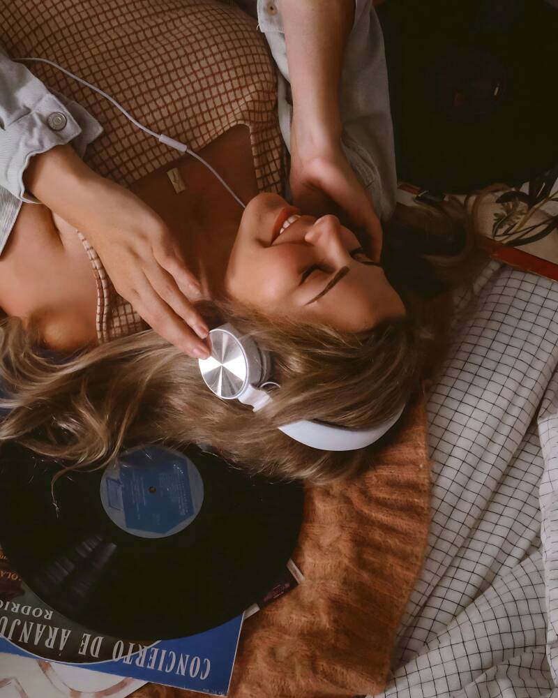 vrouw op bed luistert muziek koptelefoon