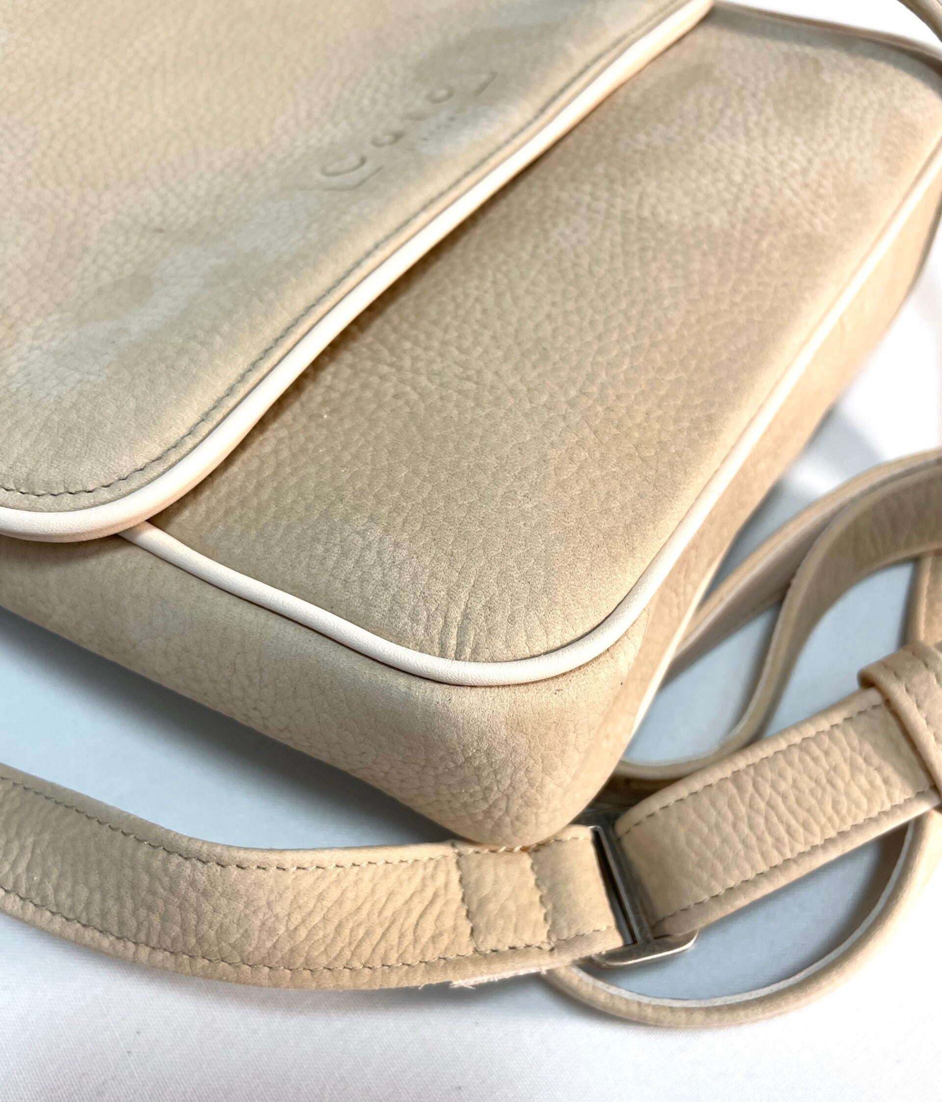 Detail van cremekleurige suède tas met klep en paspel in de naad