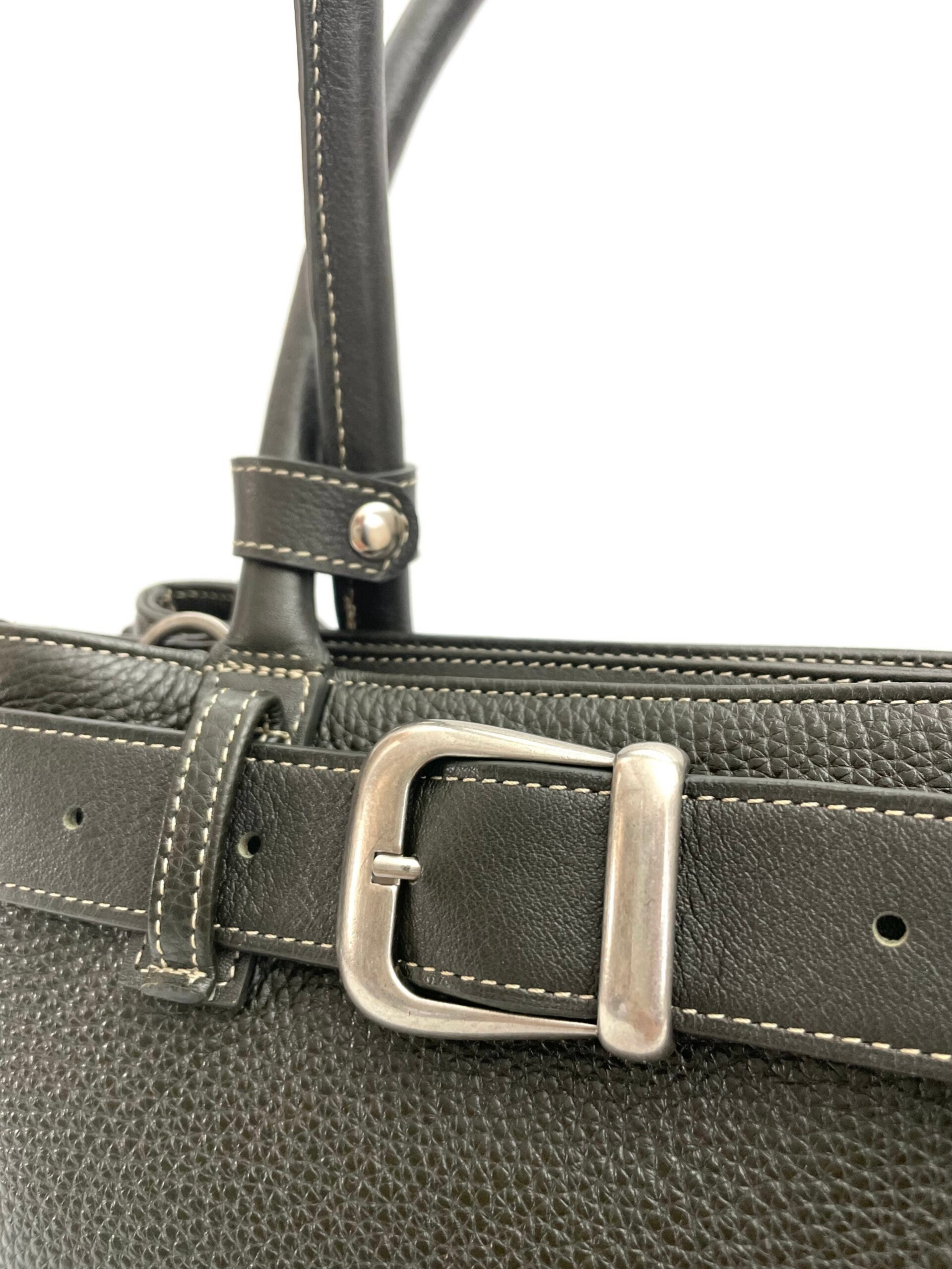 Detail van groen leren handtas met riemdecoratie