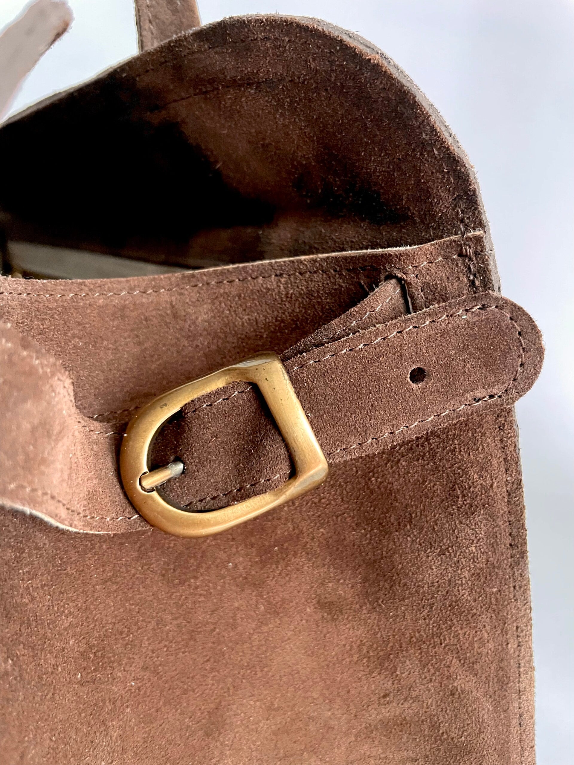 Detail van sluitriempje bruin suède totebag