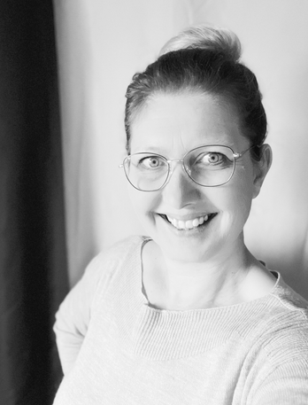 Bild von Tanja, einer Frau mit nach hinten zu einem Dutt gestyltem Haar. Sie trägt eine Brille, und schaut lächelnd in die Kamera.