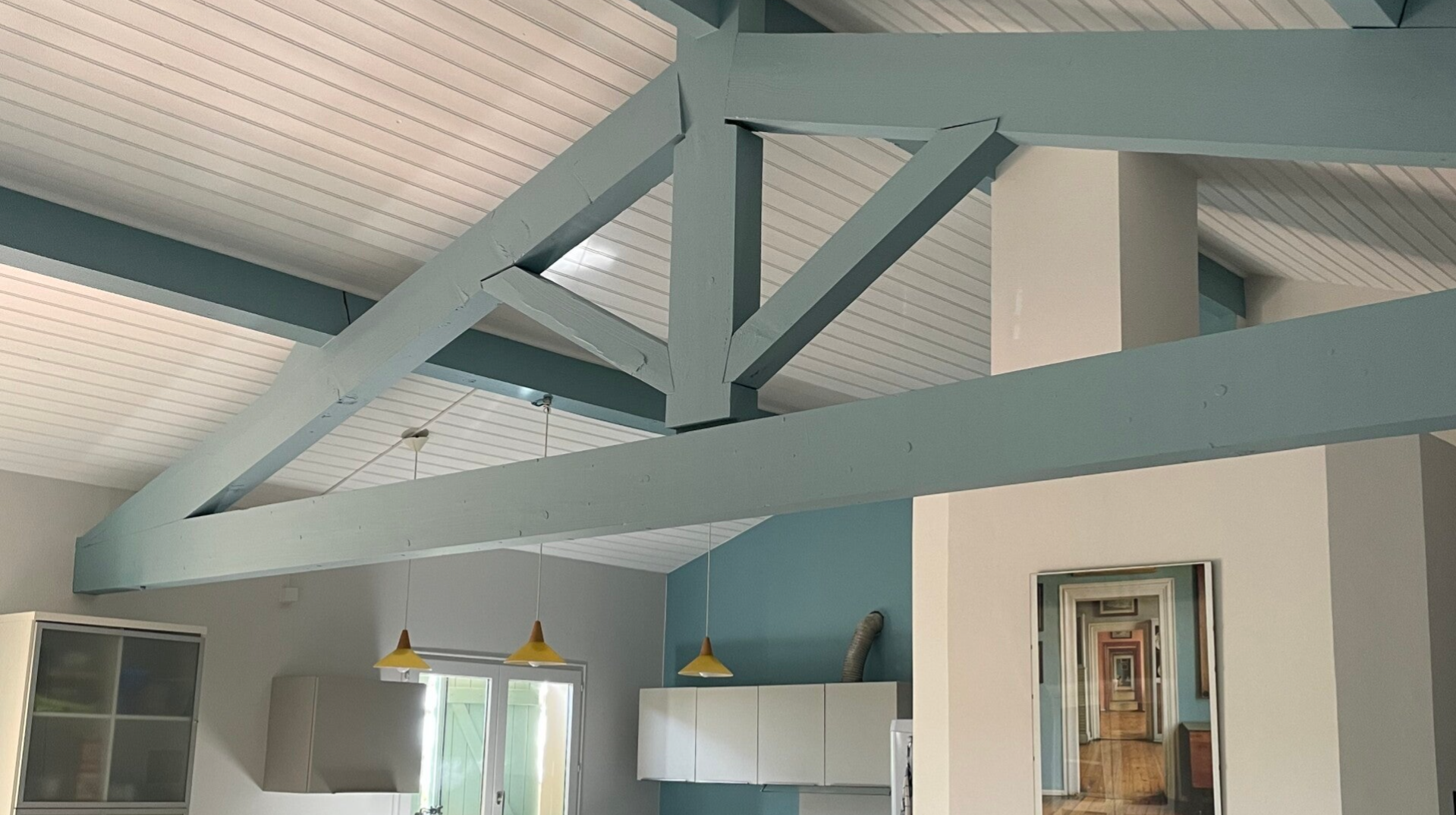 Poutres peintes en bleu grisé et plafond blanc dans une cuisine ouverte