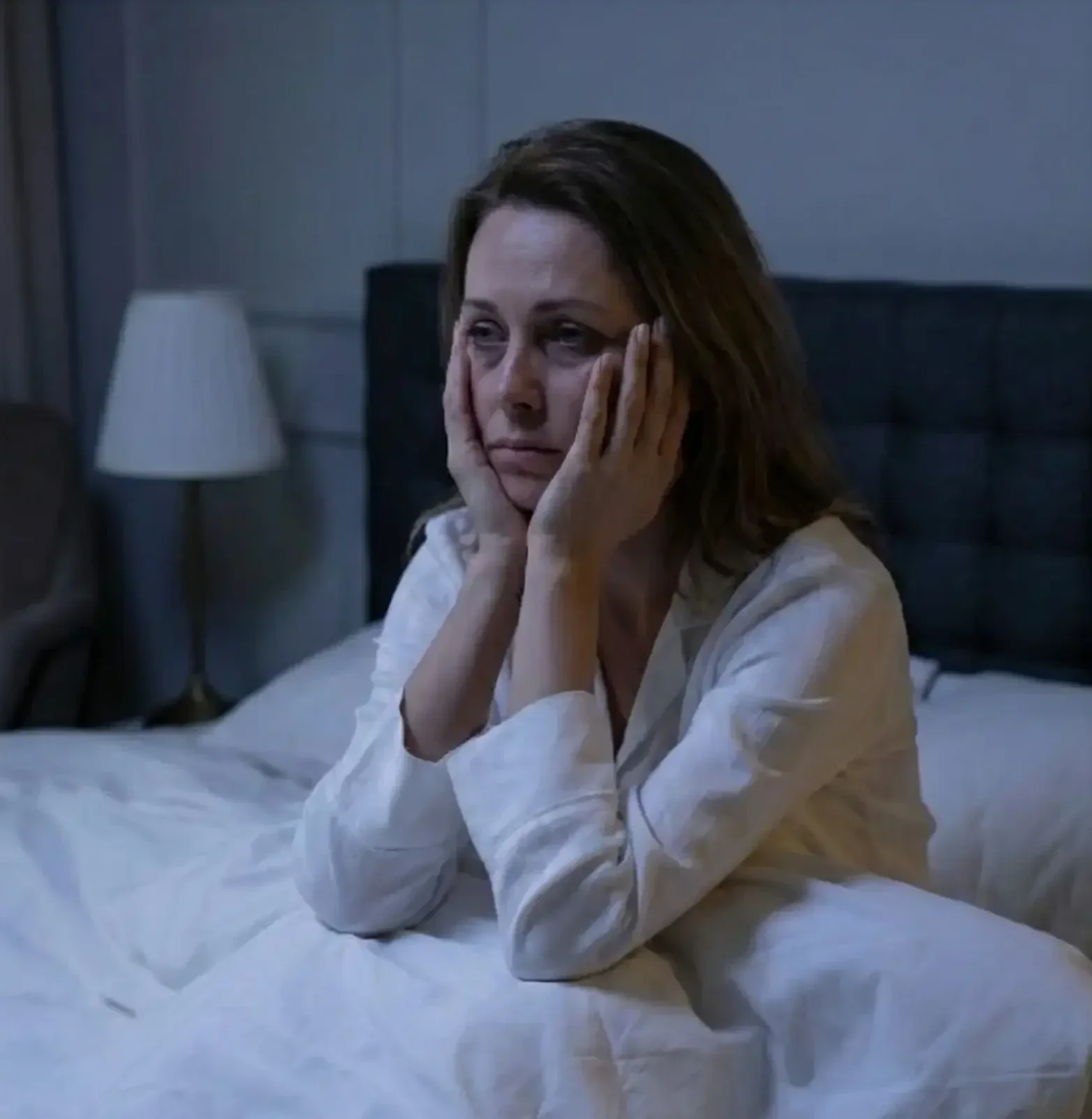 Vrouw zit rechtop in bed en kan niet slapen door piekeren - Hypnotherapie als oplossing voor slapeloosheid en insomnia