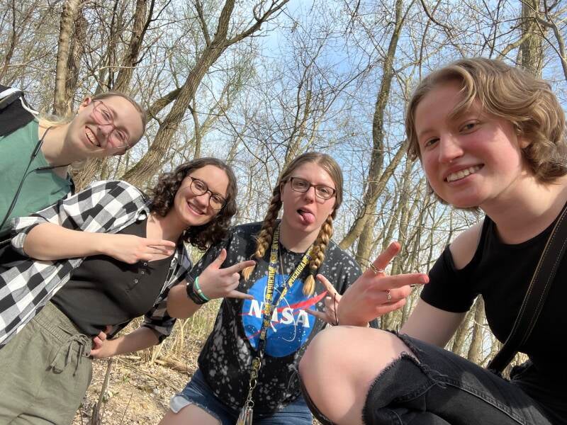 An image of 4 people in a forest smiling for a picture