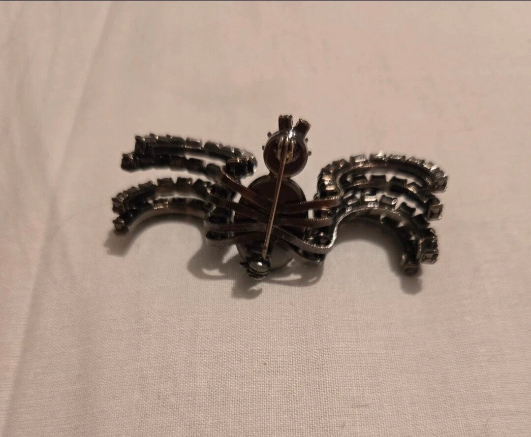 This vintage-style spider brooch features silver-tone metal and clear channel-set rhinestones, resembling 1980s designs by brands like Butler & Wilson