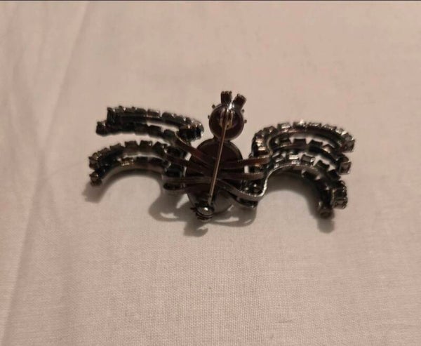 This vintage-style spider brooch features silver-tone metal and clear channel-set rhinestones, resembling 1980s designs by brands like Butler & Wilson