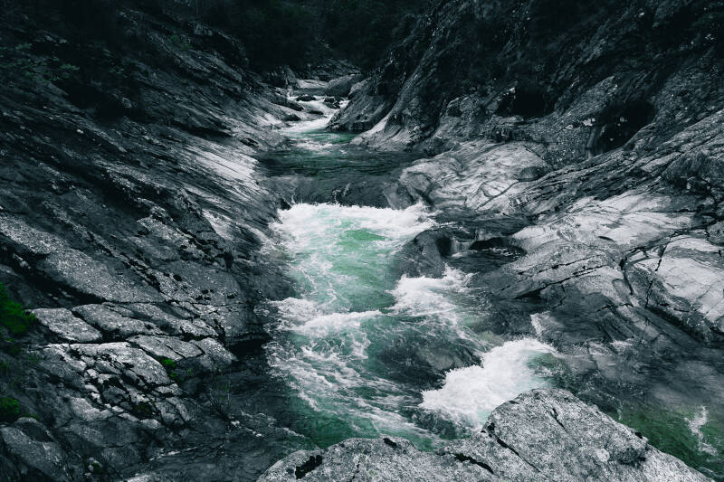 Rivière Glueyre en Ardèche, eaux émeraude s'écoulant entre les roches sombres dans un décor sauvage.