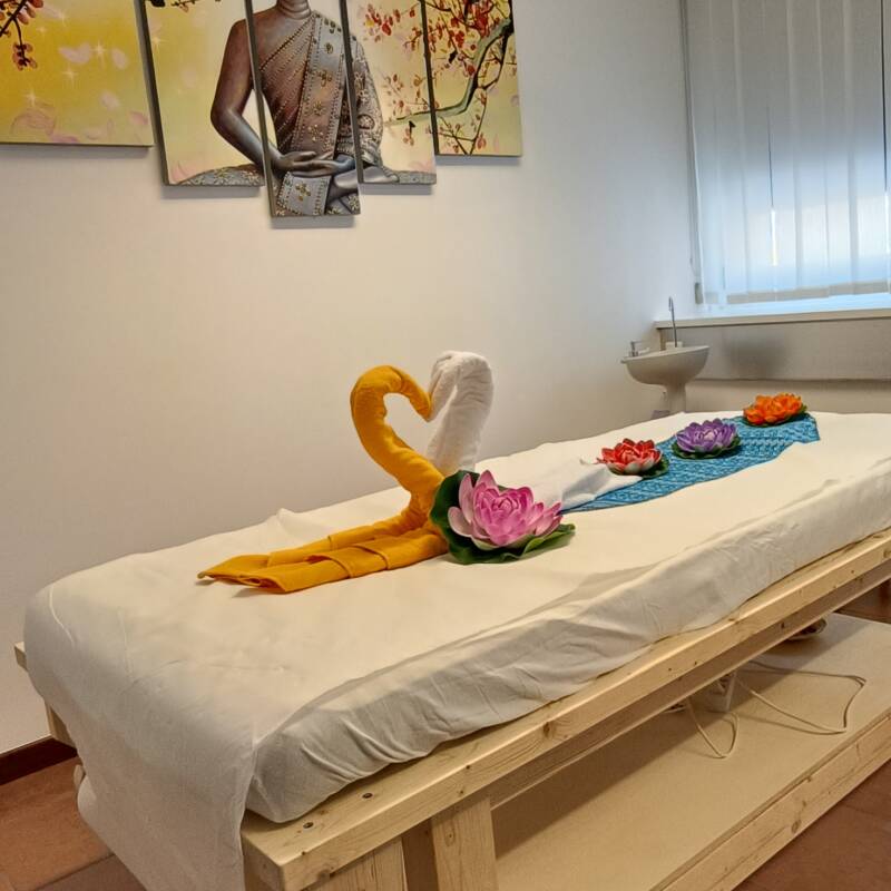 Lettino da massaggio con decorazioni di asciugamani sul lettino e quadro di Buddhaallinterno di Ooy thai massage a Lugano 