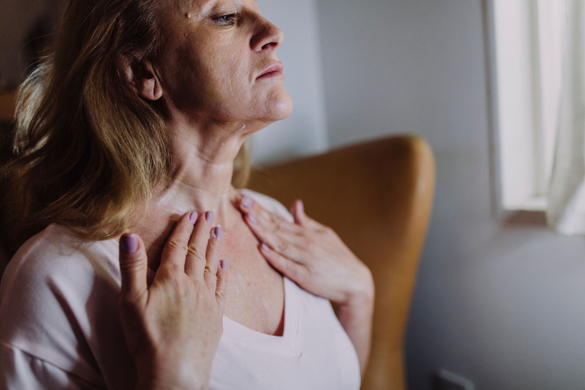 Mujer madura aplicándose crema en el cuello