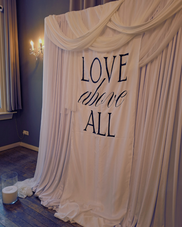 Backdrop witte draping met tekst: "Love above all"