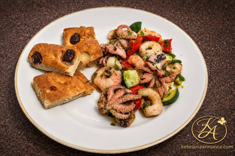 Cena chetogenica completa con insalata tiepida di totanetti e gamberoni, zucchine, peperoni e salsa verde, accompagnata da focaccia golosa alta.