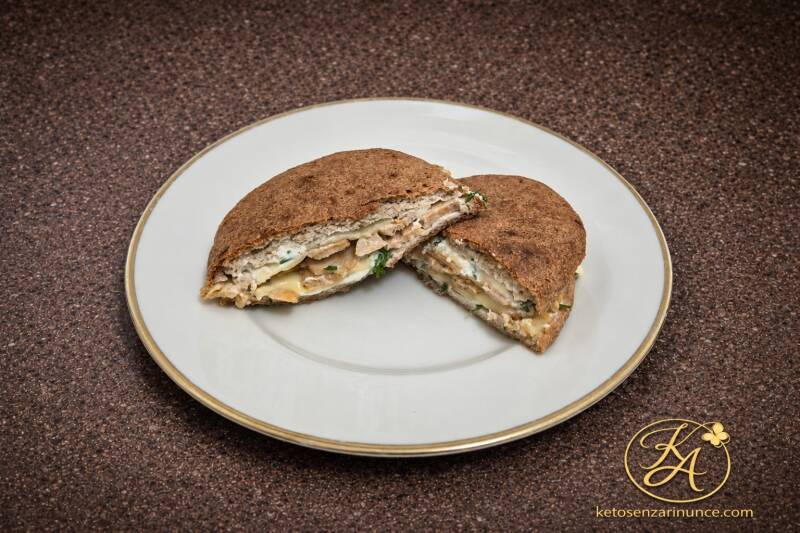 Ciabatta keto ripiena con straccetti di pollo e formaggio, servita su piatto bianco con bordo dorato su sfondo marrone elegante del blog Keto senza rinunce. Una ricetta chetogenica semplice, leggera e golosa, perfetta per pranzo, cena o colazione salata.