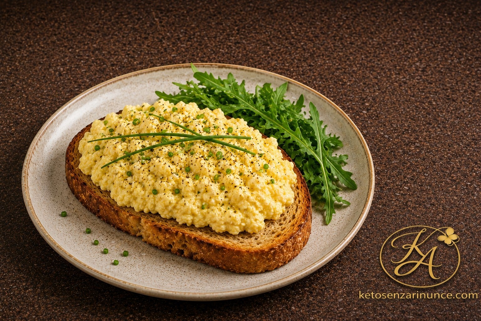 Fetta di pane alle noci chetogenico tostato con crema di uova, mozzarella e ricotta, completata da rucola fresca e una spolverata di pepe nero. Una colazione salata cremosa, nutriente e ricca di proteine, perfetta per iniziare la giornata con gusto in pie