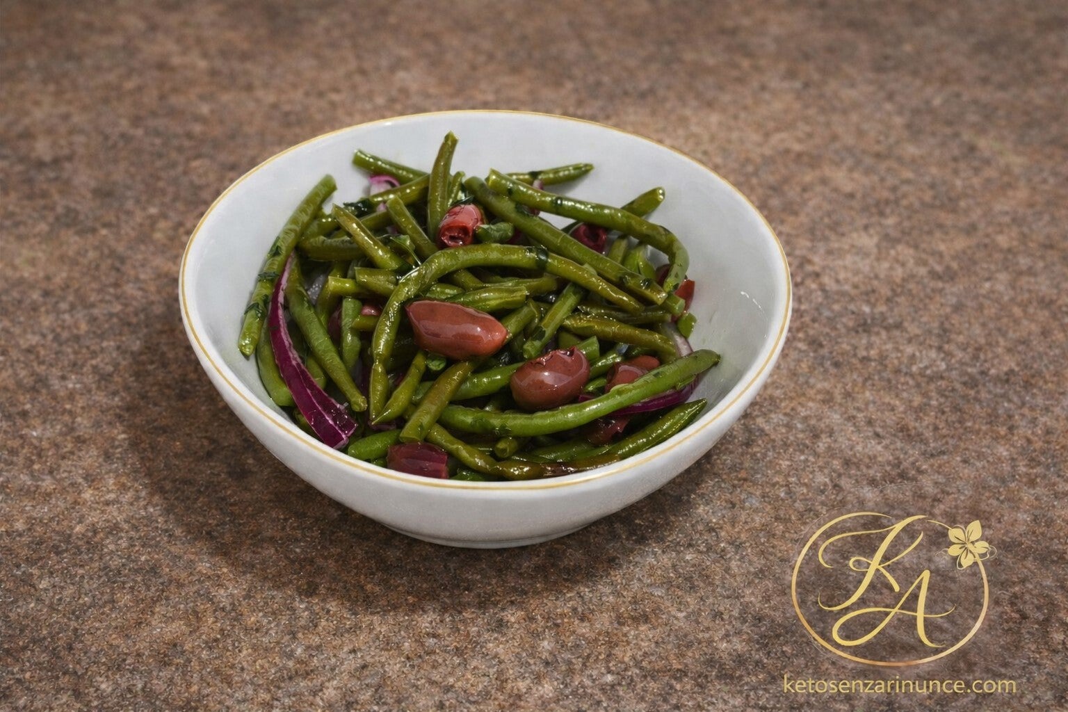Fagiolini freddi con olive e cipolla rossa conditi con olio extravergine di oliva. Un contorno chetogenico semplice, fresco e saporito perfetto per accompagnare carne o pesce.