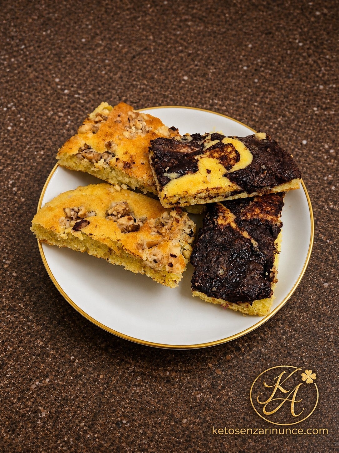 Porzione di focaccia dolce keto con varianti al cioccolato e mandorle, servita su piatto bianco con bordo dorato su sfondo marrone speckled con logo ketosenzarinunce.com.