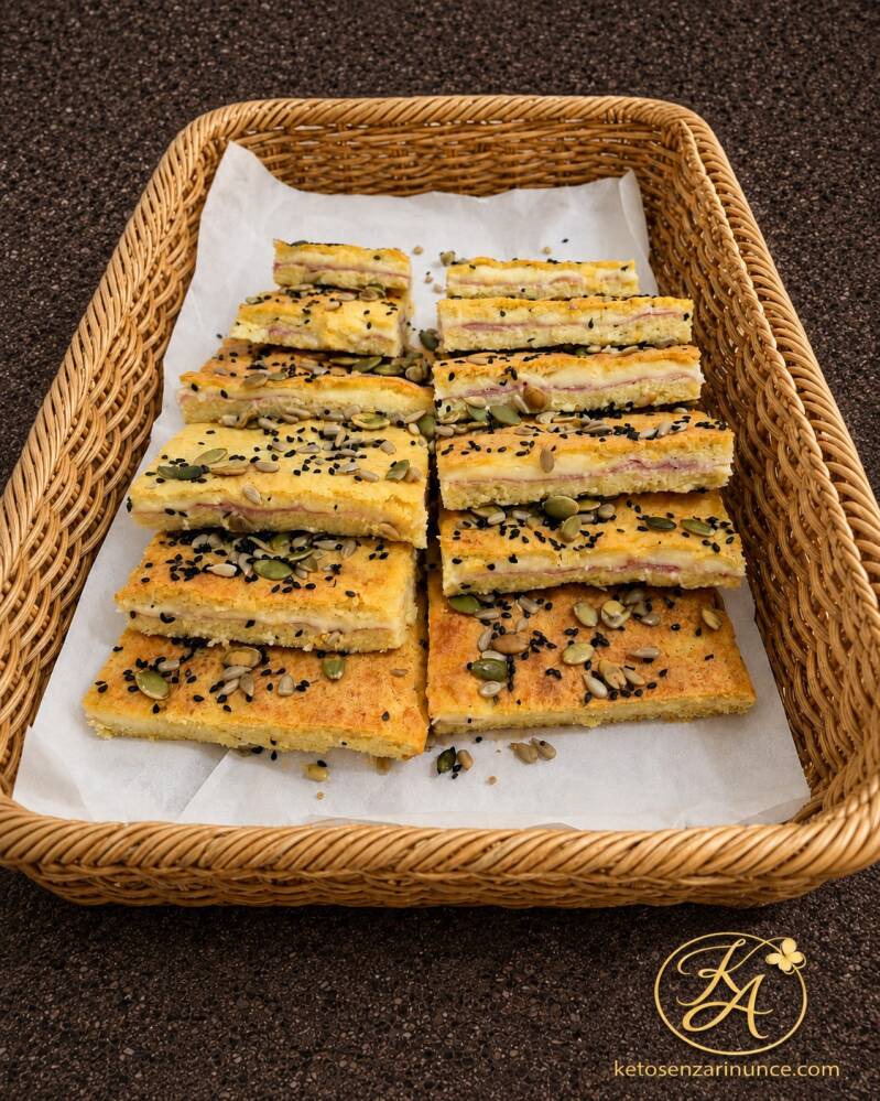Focaccia ripiena al forno alla mozzarella con prosciutto cotto e scamorza, tagliata a pezzi e servita in un cestino. Una ricetta chetogenica salata, morbida e pratica, perfetta da preparare in anticipo e portare con sé fuori casa.