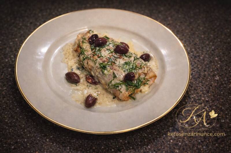 Involtino di filetto di salmone con formaggio morbido e olive nere su piatto bianco con salsa cremosa, ricetta di pesce chetogenica.