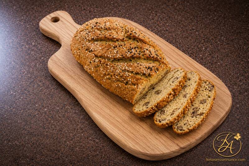 Pane chetogenico alle noci da tostare, rustico e morbido, preparato da Oxi Keto Amica su tagliere chiaro con sfondo marrone del blog ketosenzarinunce.com.