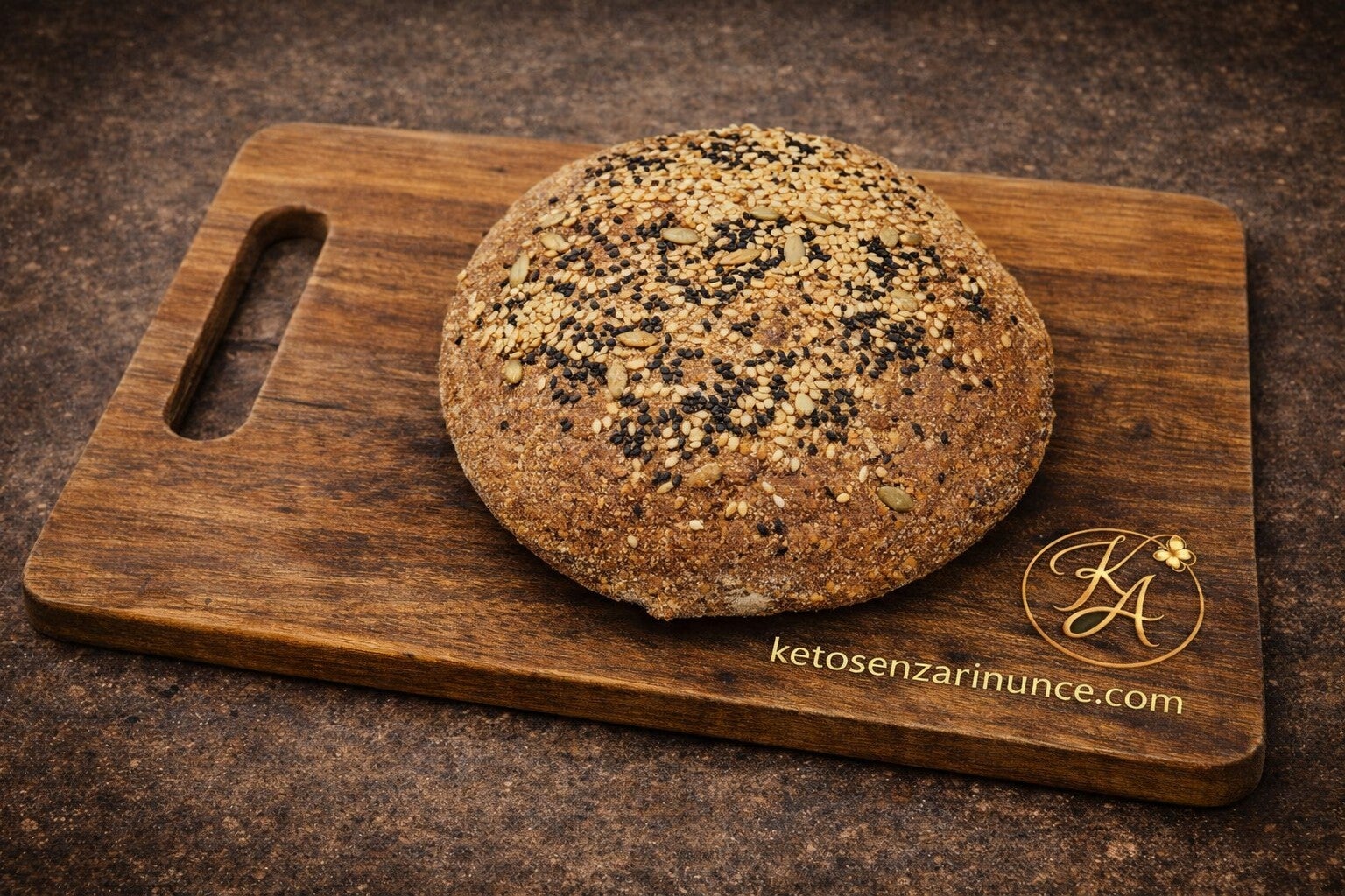 Pagnotta chetogenica al bambù intera, dalla forma rotonda e con una crosta dorata ricca di semi misti, presentata su un elegante tagliere in legno.