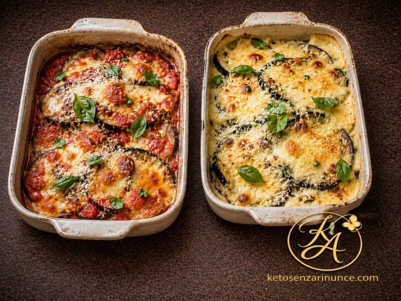 Due teglie di parmigiana di melanzane chetogenica al forno senza impanatura: una variante con pomodoro fresco, mozzarella e basilico e una variante bianca senza pomodoro, con ricotta e formaggio filante. Ricetta estiva in due versioni per Keto senza rinun