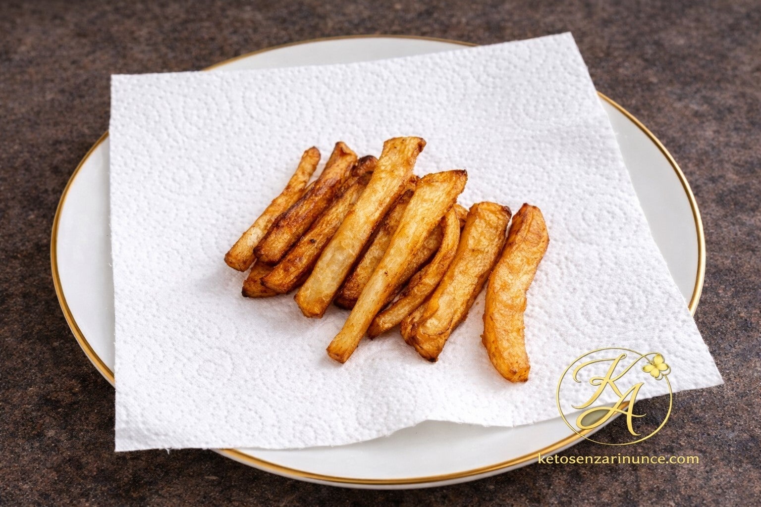 Finte patatine fritte di sedano rapa appena preparate, dorate e croccanti. Un contorno chetogenico semplice e gustoso che sostituisce le classiche patatine di patate mantenendo pochi carboidrati.