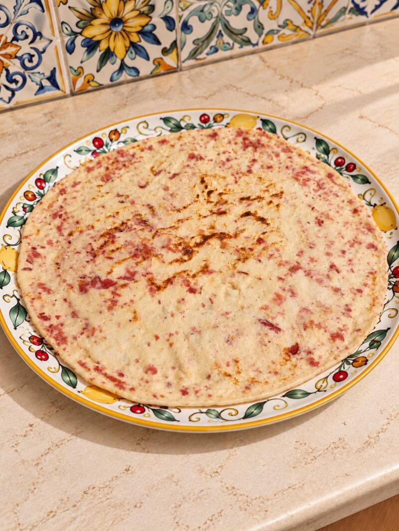 Piadina keto extra sottile allo speck, stesa finemente e cotta in padella da 32 cm. Morbida, flessibile e facile da arrotolare, preparata senza uova e senza latticini nell’impasto. Base versatile per farciture salate e altre ricette chetogeniche.