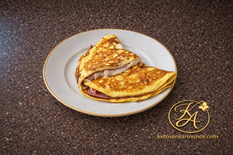 Piadina omelette keto farcita con prosciutto crudo e formaggio, cotta in padella e servita su piatto chiaro. Una proposta salata semplice, veloce e molto gustosa, ideale per colazione, brunch o pasto leggero.