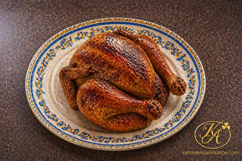 Pollo arrosto all’aglio e origano, dorato e profumato, servito su piatto mediterraneo sullo sfondo ufficiale del blog Keto senza rinunce.