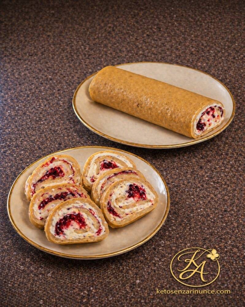 Rotolo dolce del mattino farcito con crema e frutti rossi, servito intero e a fette su due piatti eleganti.