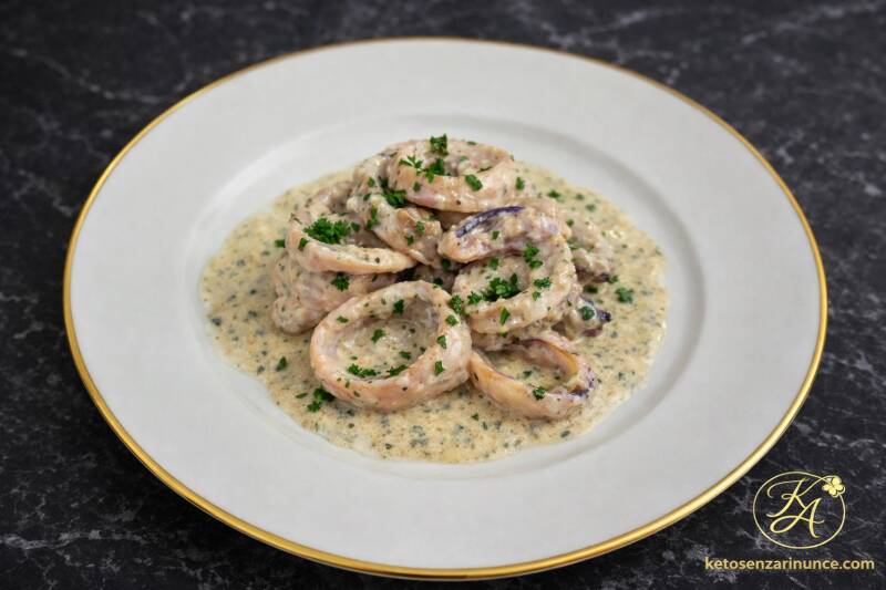 Seppie cremose alla crema di formaggio servite su piatto bianco con bordo oro, una ricetta chetogenica semplice e saporita, con salsa morbida e avvolgente perfetta per un secondo piatto keto di pesce.