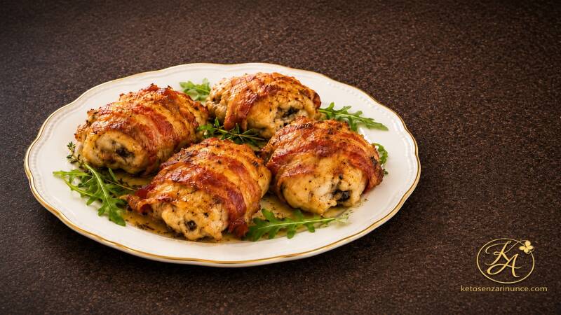 Sovracosce di pollo al forno avvolte nel bacon, servite su piatto elegante con misticanza fresca, ricetta chetogenica semplice e golosa.