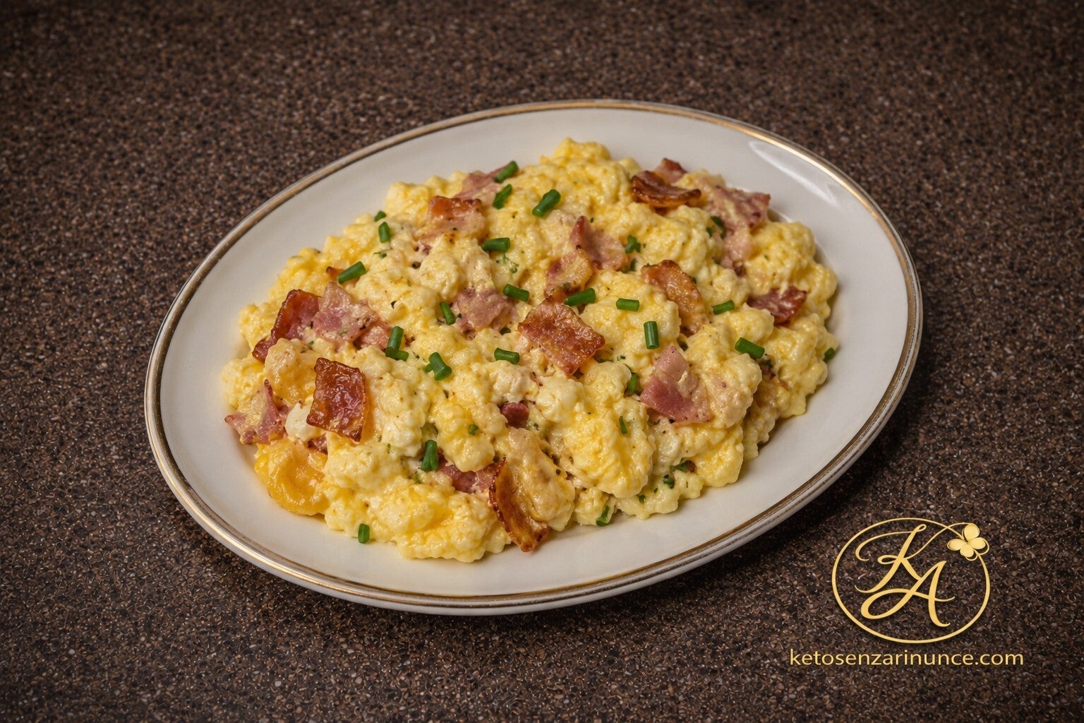 Uova strapazzate cremose con bacon croccante, formaggio spalmabile ed erba cipollina, servite su piatto bianco con bordo dorato.