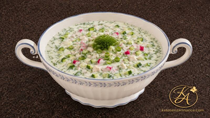 Zuppa fredda estiva keto servita in un’elegante zuppiera bianca con delicati decori blu. Una ricetta fresca e cremosa preparata con kefir naturale senza zuccheri aggiunti, cetriolo, ravanelli, uova, pollo, cipollotto e aneto fresco, ideale per un pranzo o