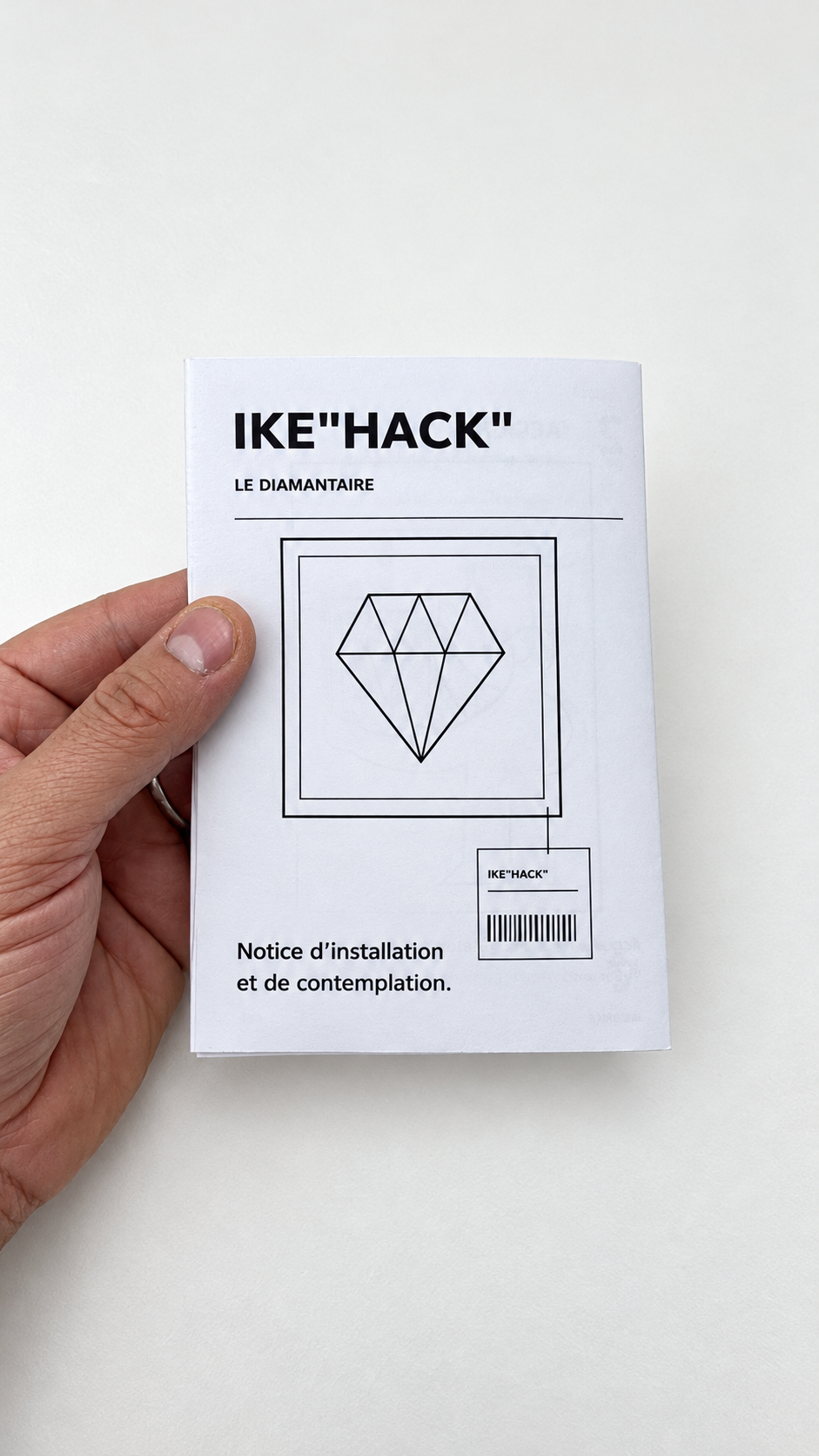 La notice IKE"hack" tenue à la main, avec un dessin de diamant encadré en couverture.