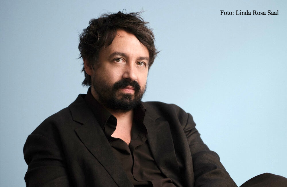 Victor Le Masne im schwarzem Hemd und Sakko vor blauem Hintergrund | Die Review im Vinyl-Fan Blog