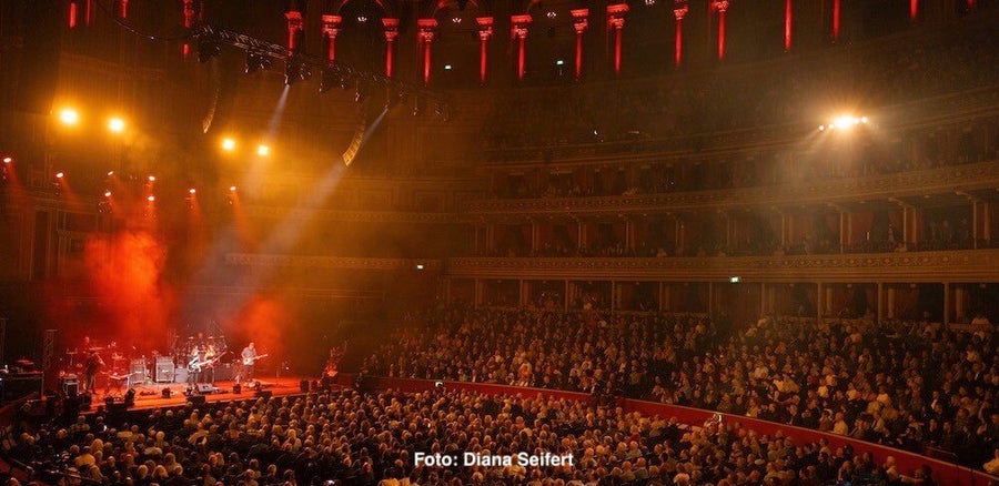 Steve Hackett und seine Band live in der Royal Albert Hall im roten Scheinwerferlicht und Blick auf das Publikum | DIe Review im Vinyl-Fan Blog zu "The Lamb Stands Up Live At The Royal Albert Hall"