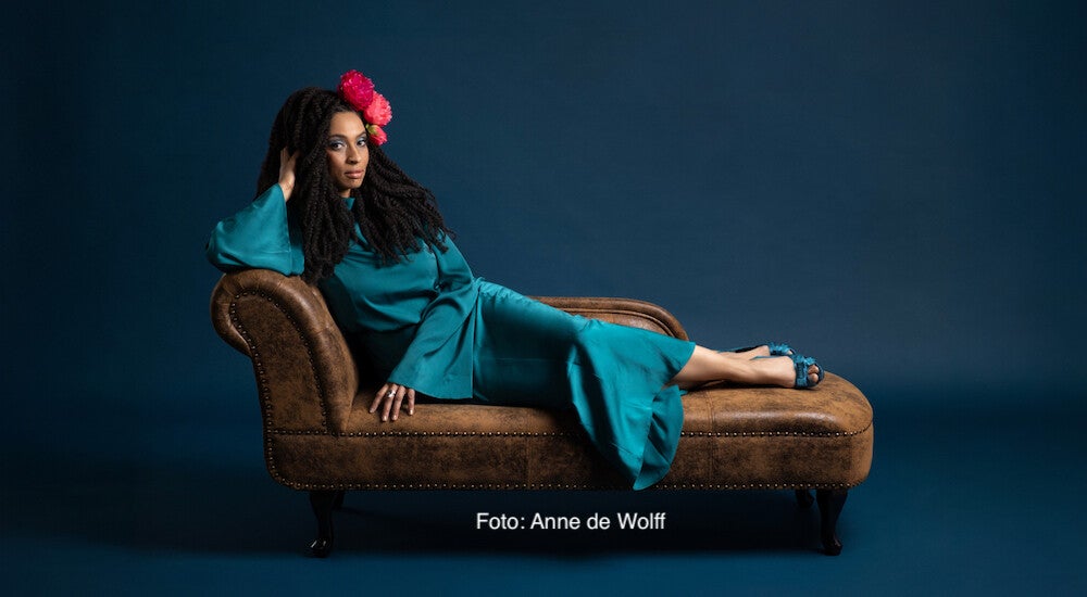 Tokunbo im blauen Kleid liegt auf einem braunen Sofa | Foto: Anne de Wolff