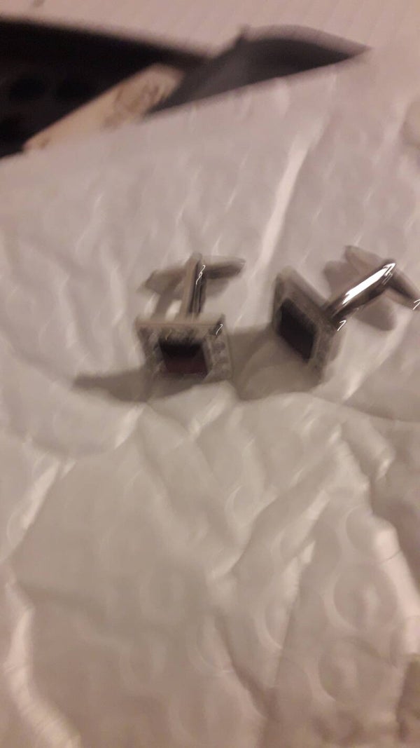 Silver metal plated mans cuff links new with red stone in n pattern square.