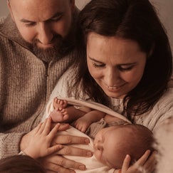 Neugeborenes liegt in den Armen von Mama und Papa beim Neugeborenen Shooting in Berlin