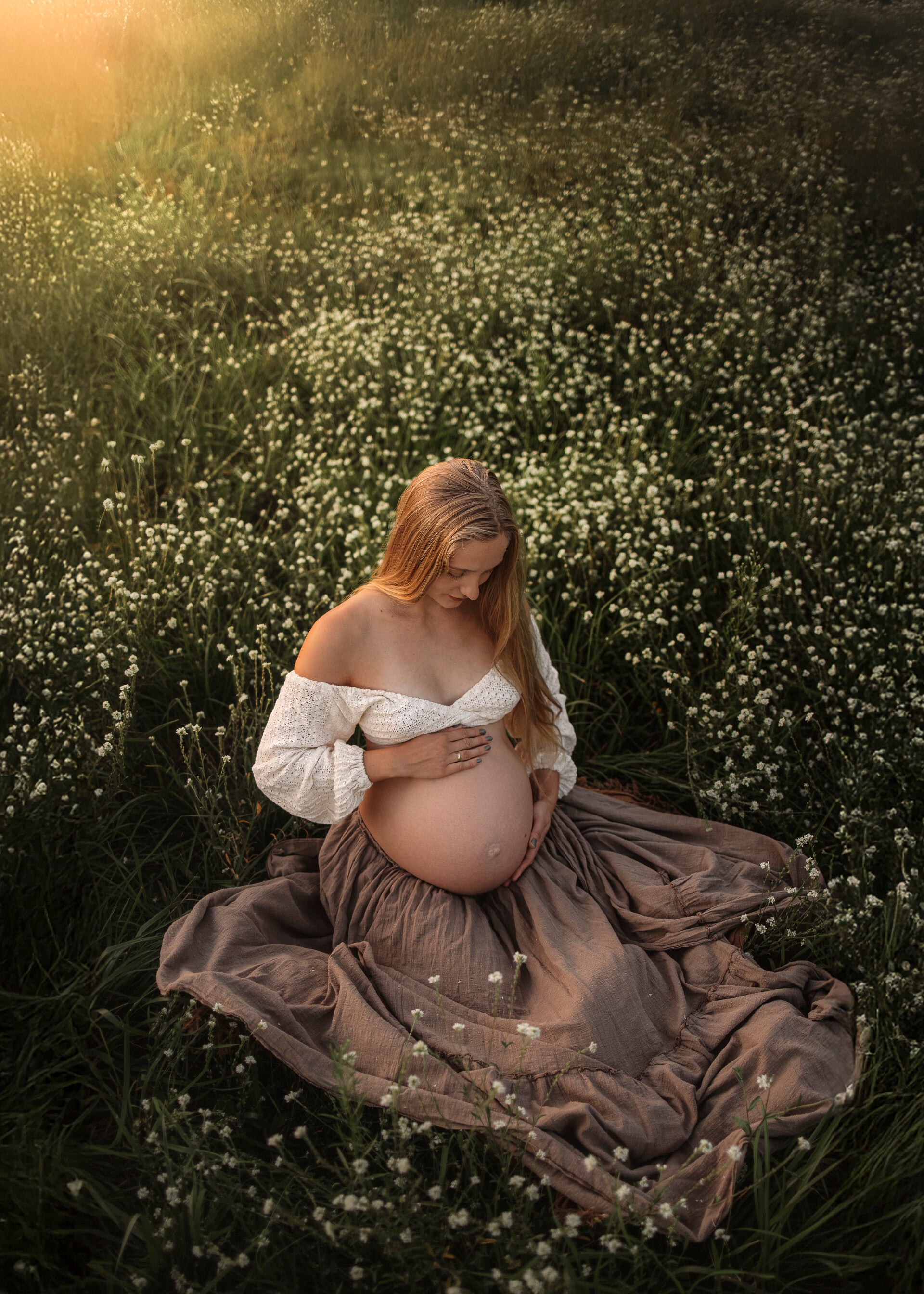 Pärchen steht in vertrauter Pose am wasser und blickt auf den Babybauch beim Babybauchshooting in Berlin 